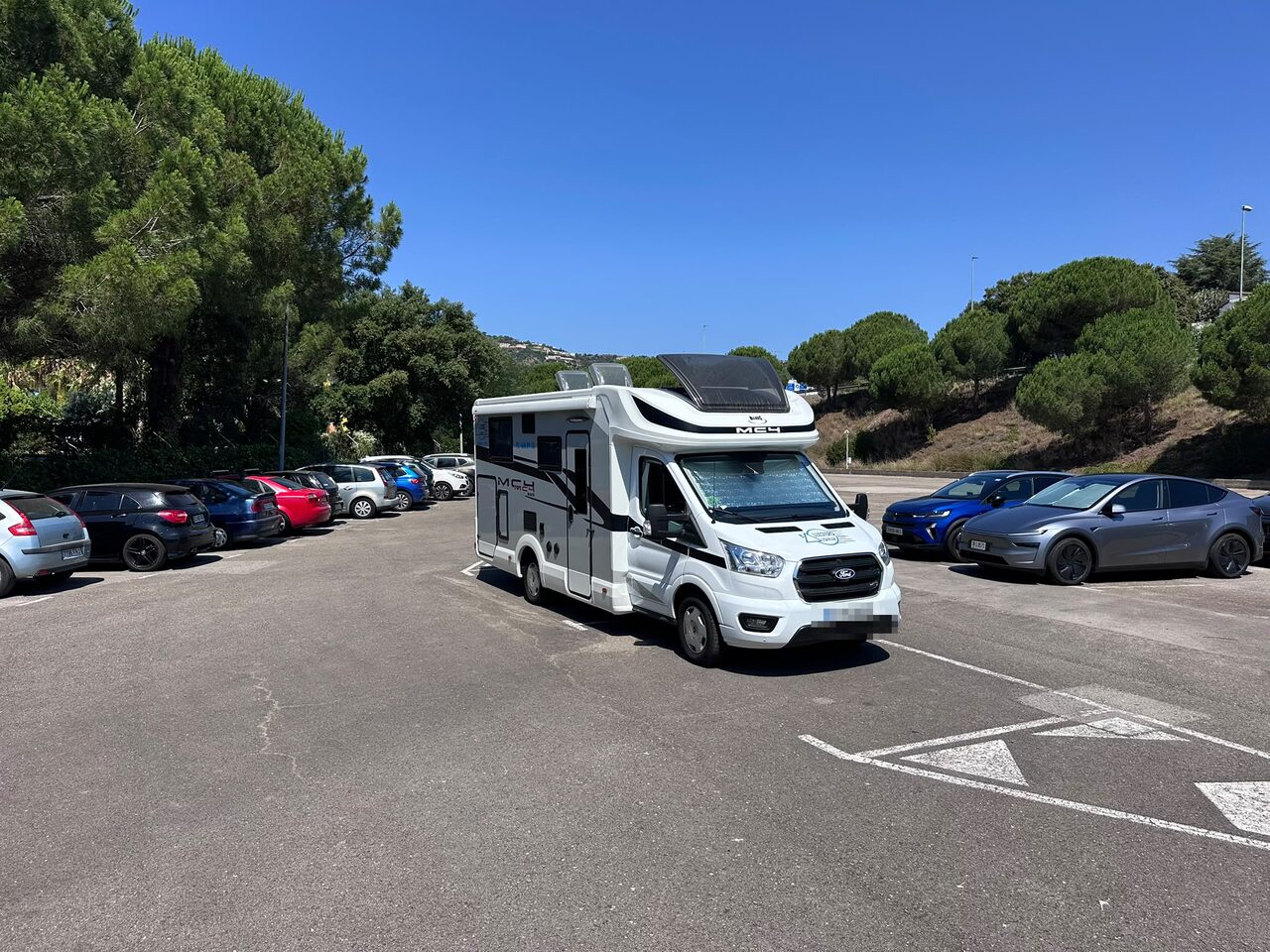 Alquiler de autocaravana en la Costa Brava aparcada entre pinos cerca de la playa